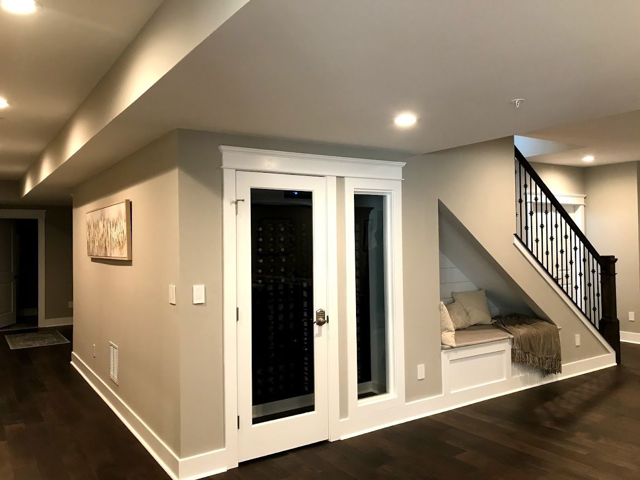 A basement with a staircase and a bench under the stairs.