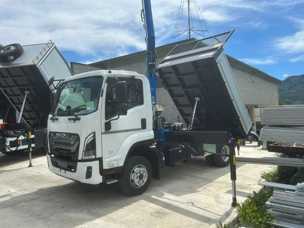 Un camion bianco con gru e pianale di carico sollevato, parcheggiato in un parcheggio all'aperto in una giornata di sole.