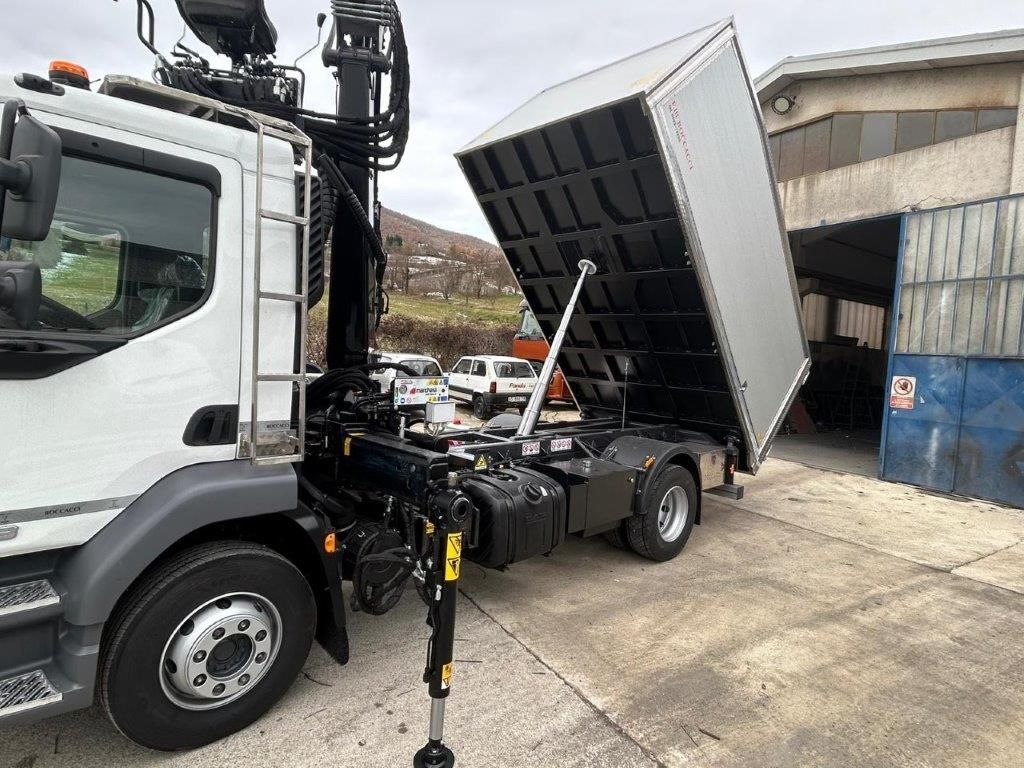 Un autocarro ribaltabile bianco con gru, parcheggiato in un piazzale con il cassone sollevato in posizione verticale.