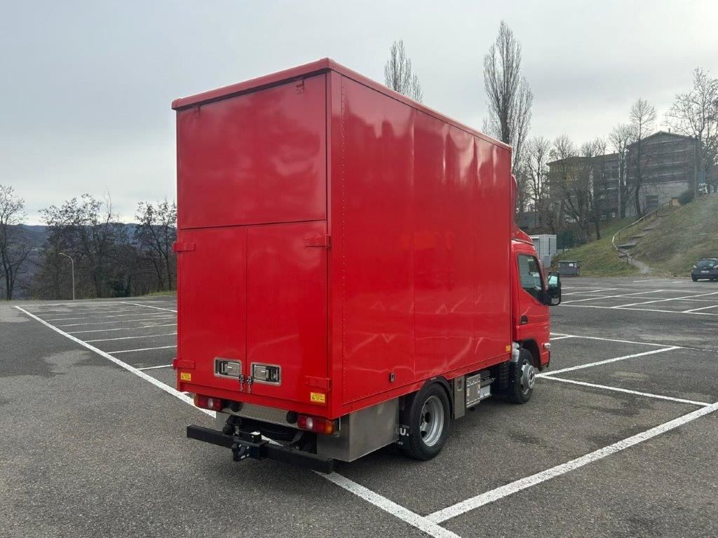 Un furgone rosso parcheggiato in un parcheggio esterno vuoto in una giornata nuvolosa.