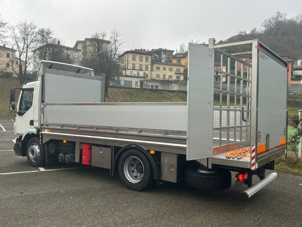 Un camioncino bianco a pianale con sponda posteriore a rete, parcheggiato in un piazzale asfaltato, visto di lato e da dietro.