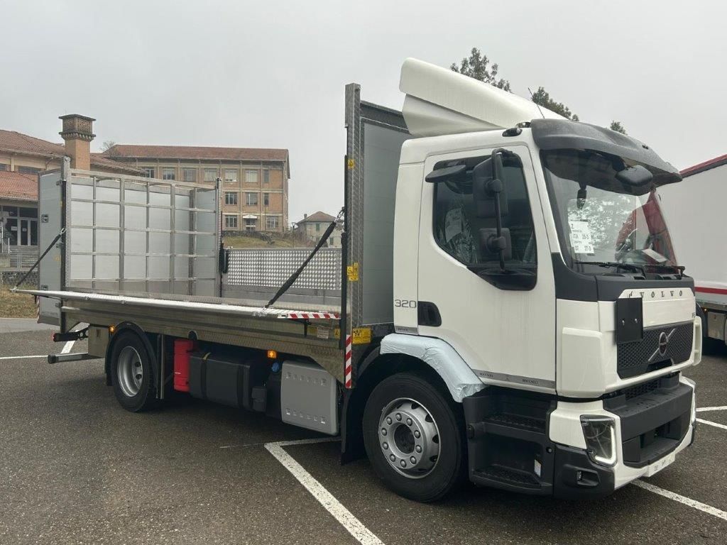 Un camioncino bianco con pianale ribassato parcheggiato in un parcheggio all'aperto in una giornata nuvolosa.