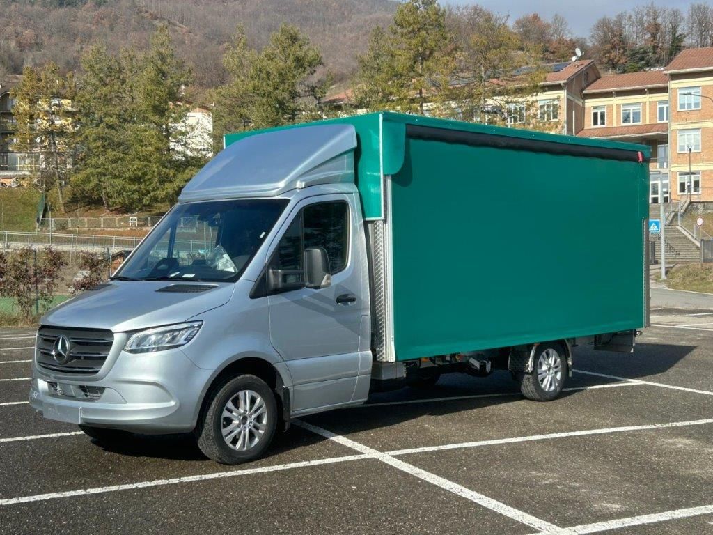 Un camion bianco con un grande serbatoio cilindrico in acciaio inossidabile parcheggiato all'aperto vicino a dolci colline verdi.