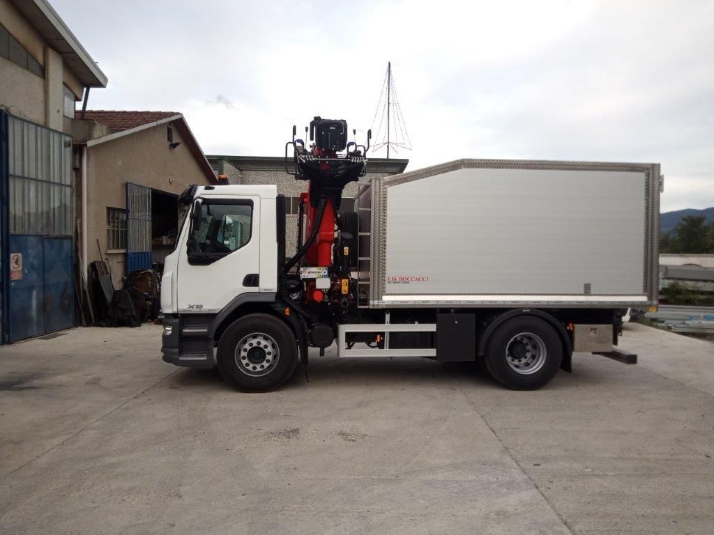 Un camion bianco con una gru montata dietro la cabina e un grande cassone chiuso, parcheggiato su un piazzale asfaltato.