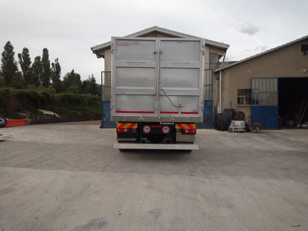 Un furgone argentato visto da dietro, parcheggiato su un piazzale di cemento di fronte a un edificio.