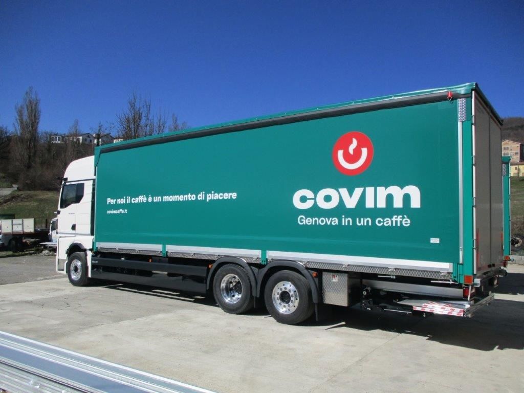 Un semirimorchio color verde acqua con il logo e la scritta 