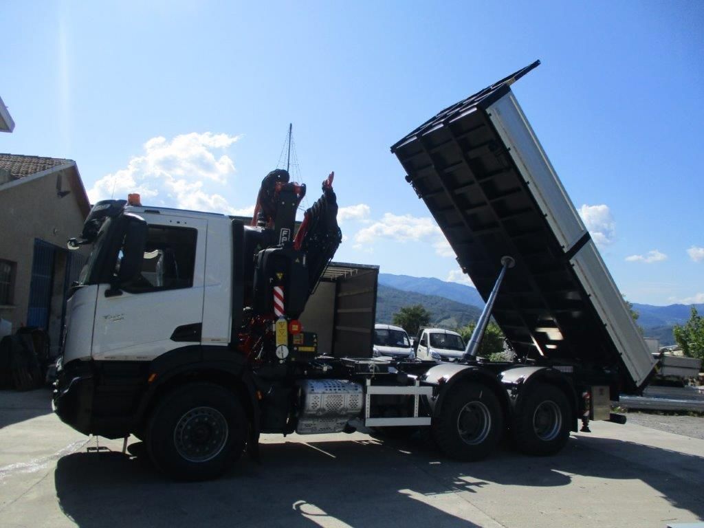 Un autocarro ribaltabile Scania bianco con gru, parcheggiato all'aperto, con il cassone inclinato verso l'alto.