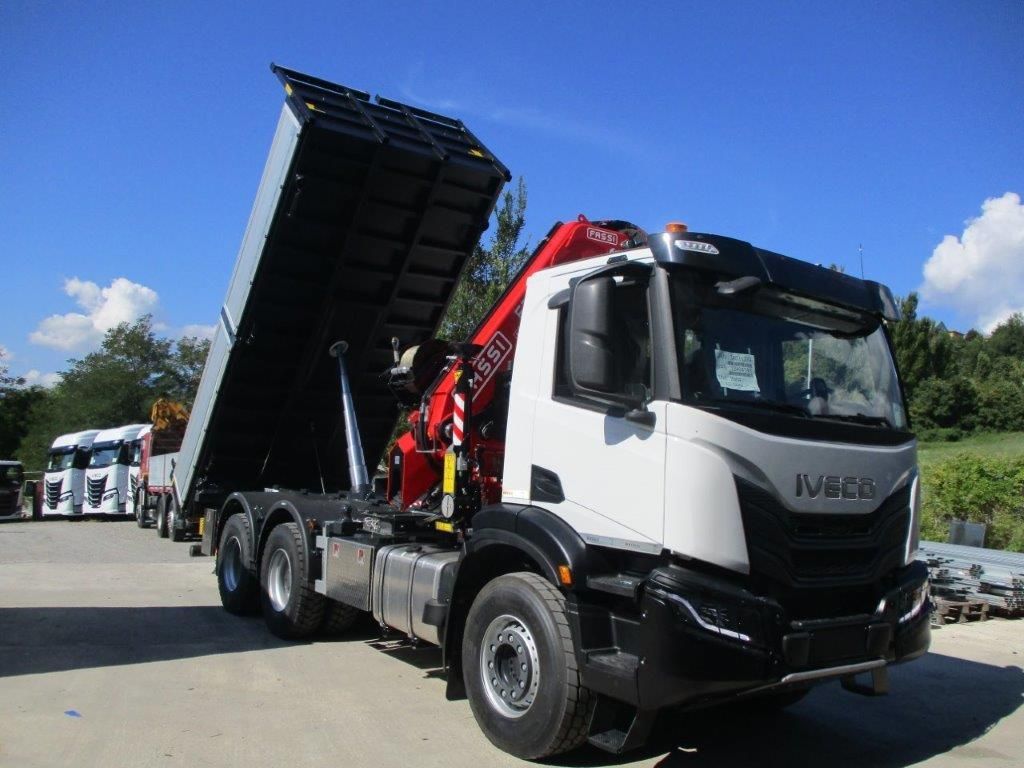 Un camion ribaltabile Iveco bianco con il cassone sollevato, parcheggiato all'aperto in una giornata di sole.