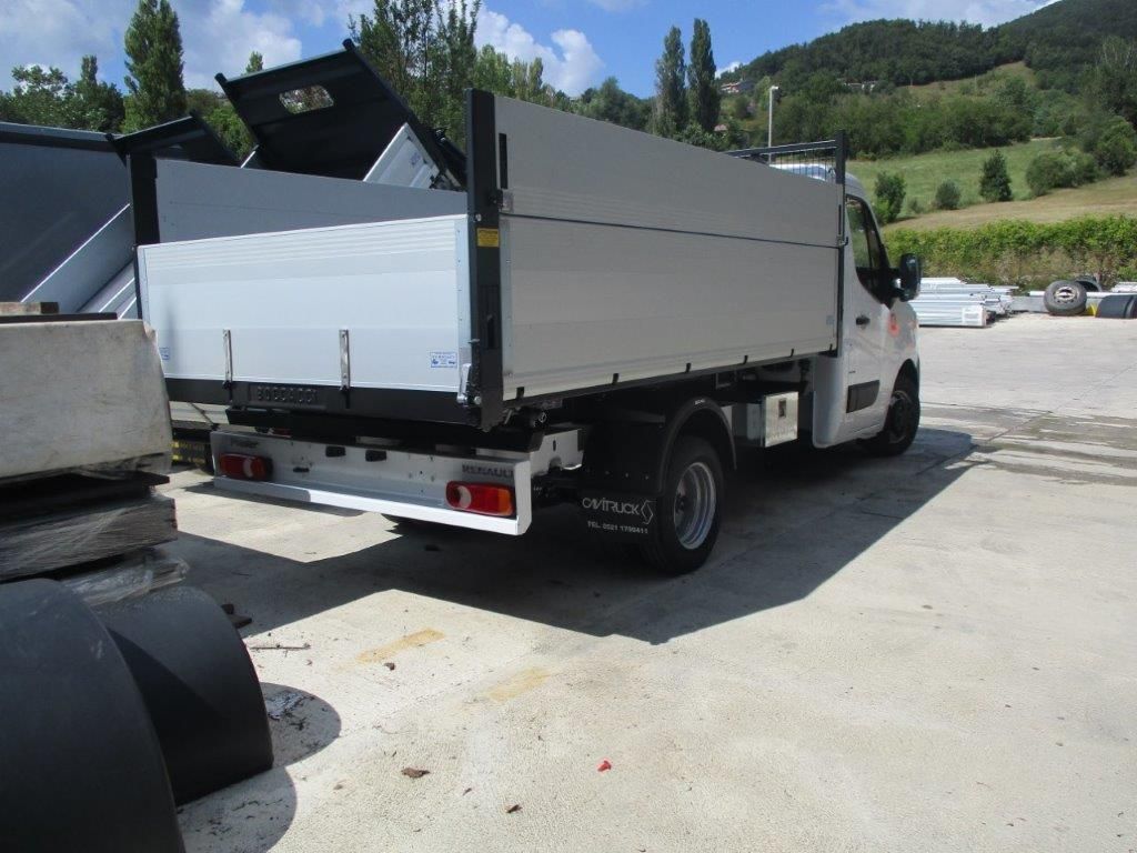 Un autocarro ribaltabile bianco parcheggiato su un piazzale ghiaioso sotto un cielo azzurro e limpido, visto dal lato posteriore del passeggero.