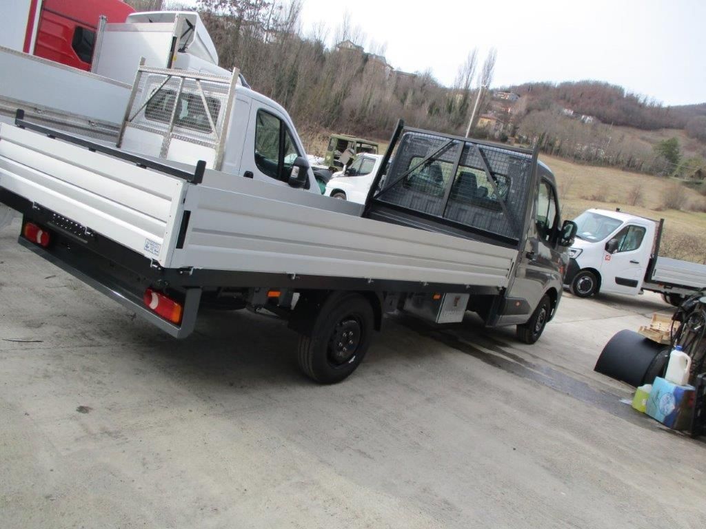 Un camion a pianale ribassato parcheggiato in un parcheggio all'aperto, con altri veicoli commerciali nelle vicinanze.