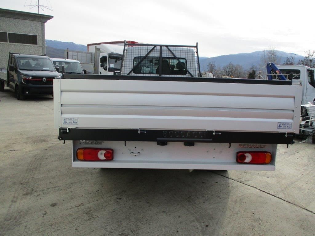 Un camioncino bianco a pianale ribassato parcheggiato all'aperto, che mostra il cassone posteriore, i fanali posteriori e la sponda anteriore della cabina.