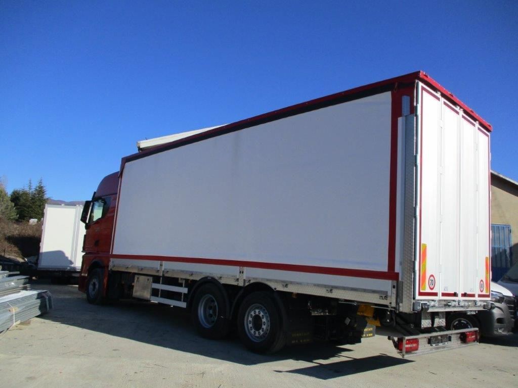 Un furgone rosso e bianco parcheggiato su un piazzale ghiaioso sotto un cielo azzurro e limpido.