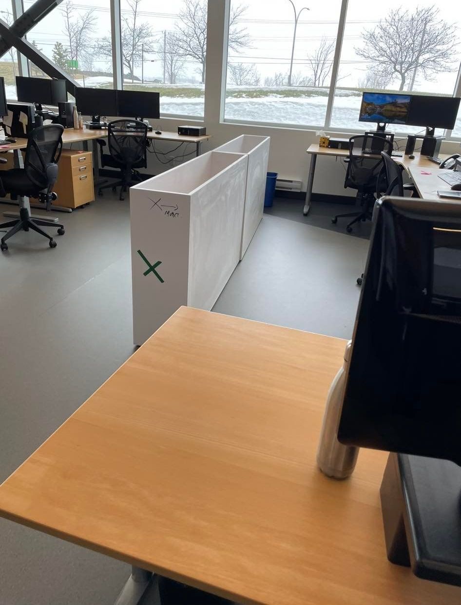 Bureau cloisonné avec cloisons en carton. Bureaux, écrans, chaises et fenêtre avec vue.