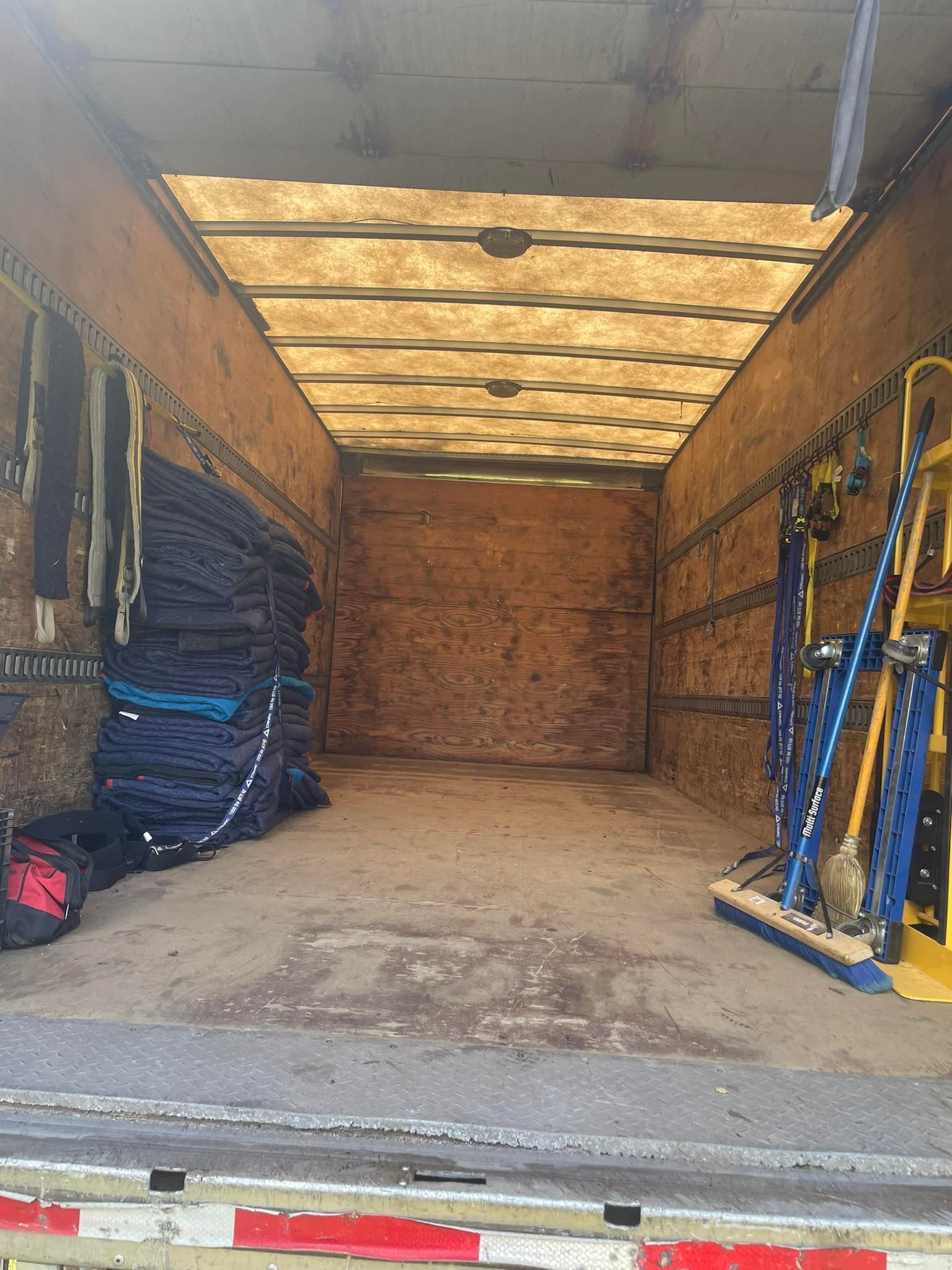 Intérieur d'une benne de camion; divers outils et équipements sont rangés le long des murs, boiseries, zone de chargement.