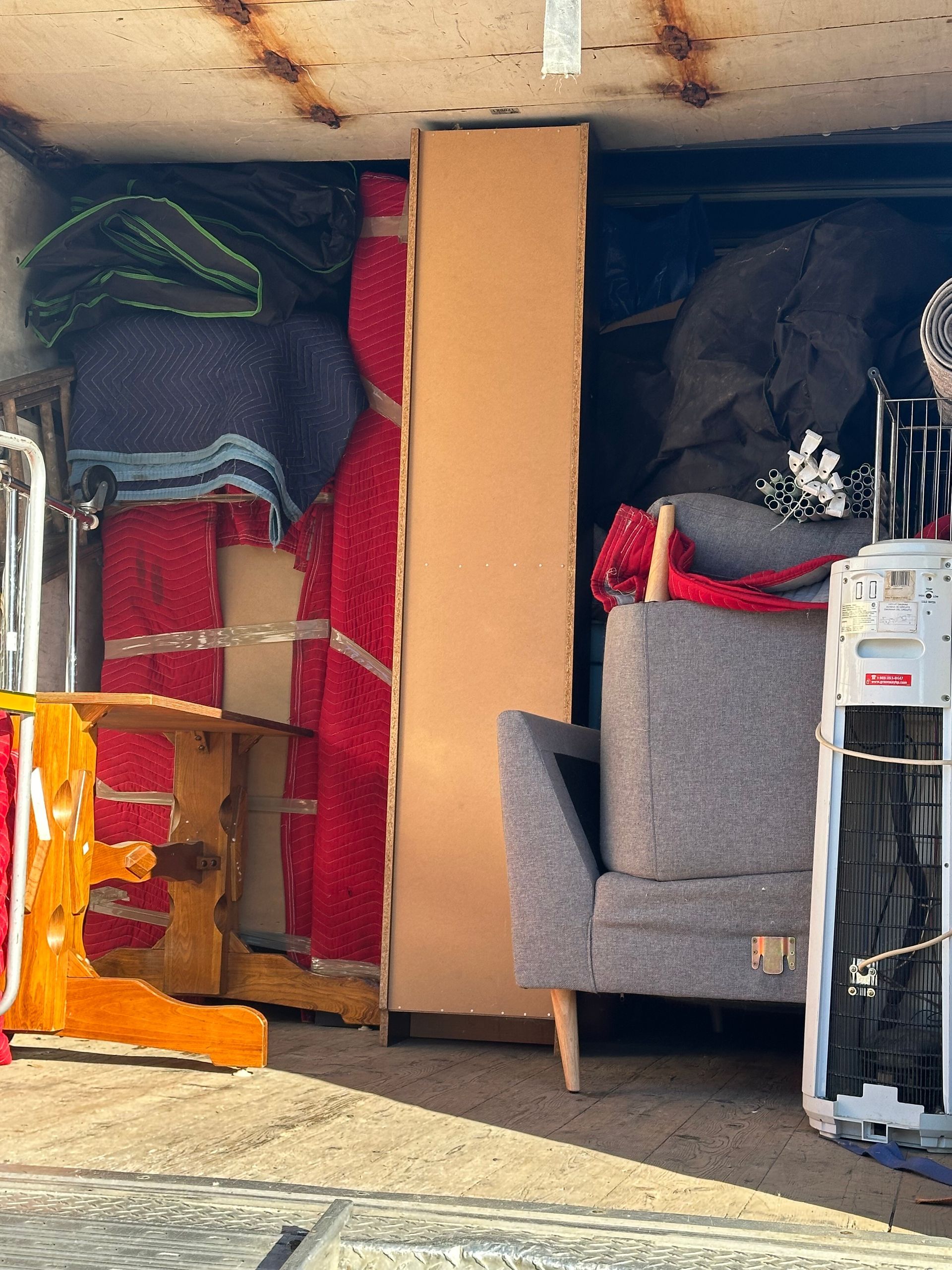 Un camion de déménagement rempli : meubles, cartons et effets personnels sont à l'intérieur, prêts à être transportés.