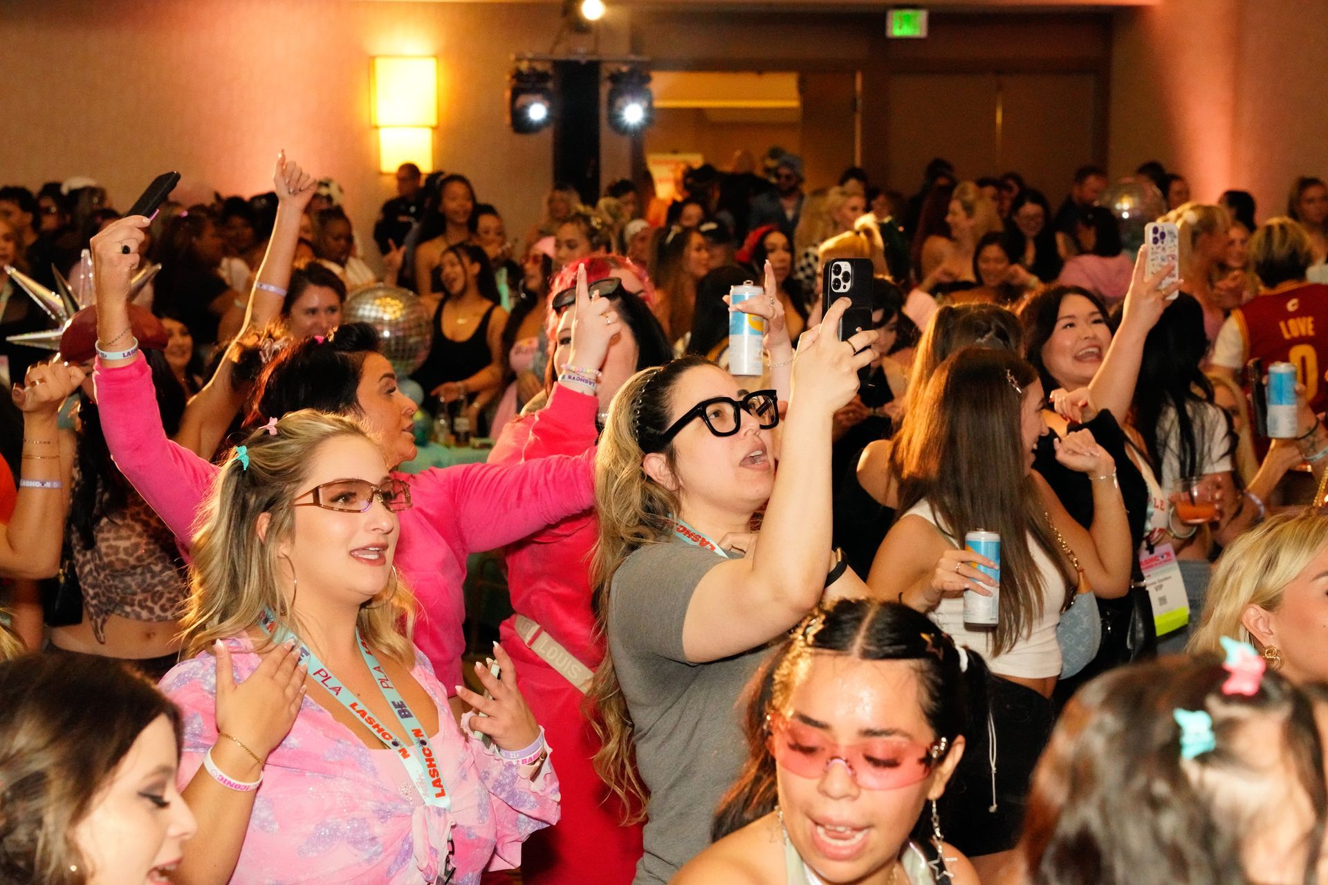 A crowd of people are dancing and taking pictures at a party.