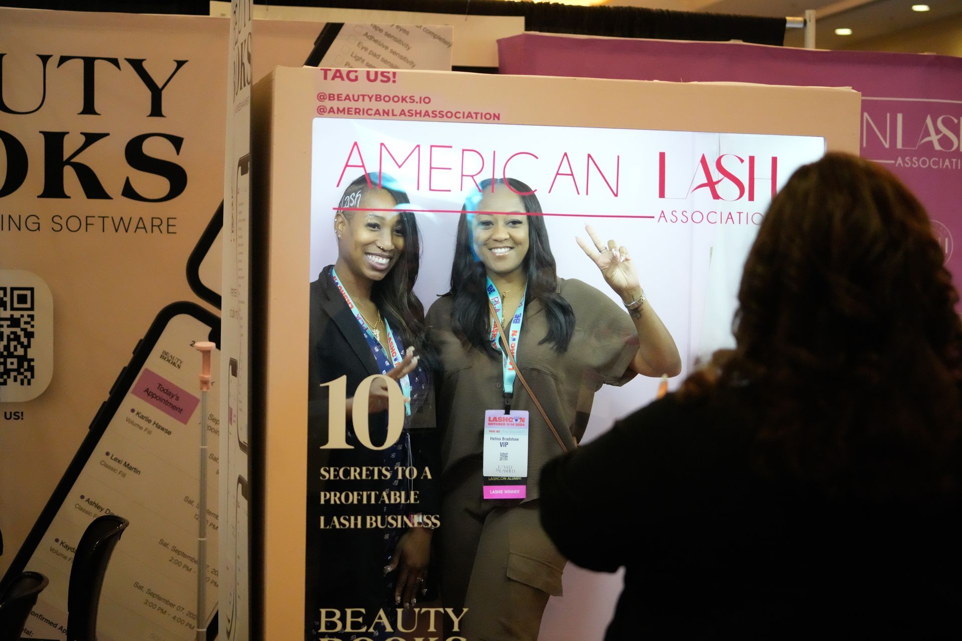 A woman is taking a picture of two women in front of a mirror.