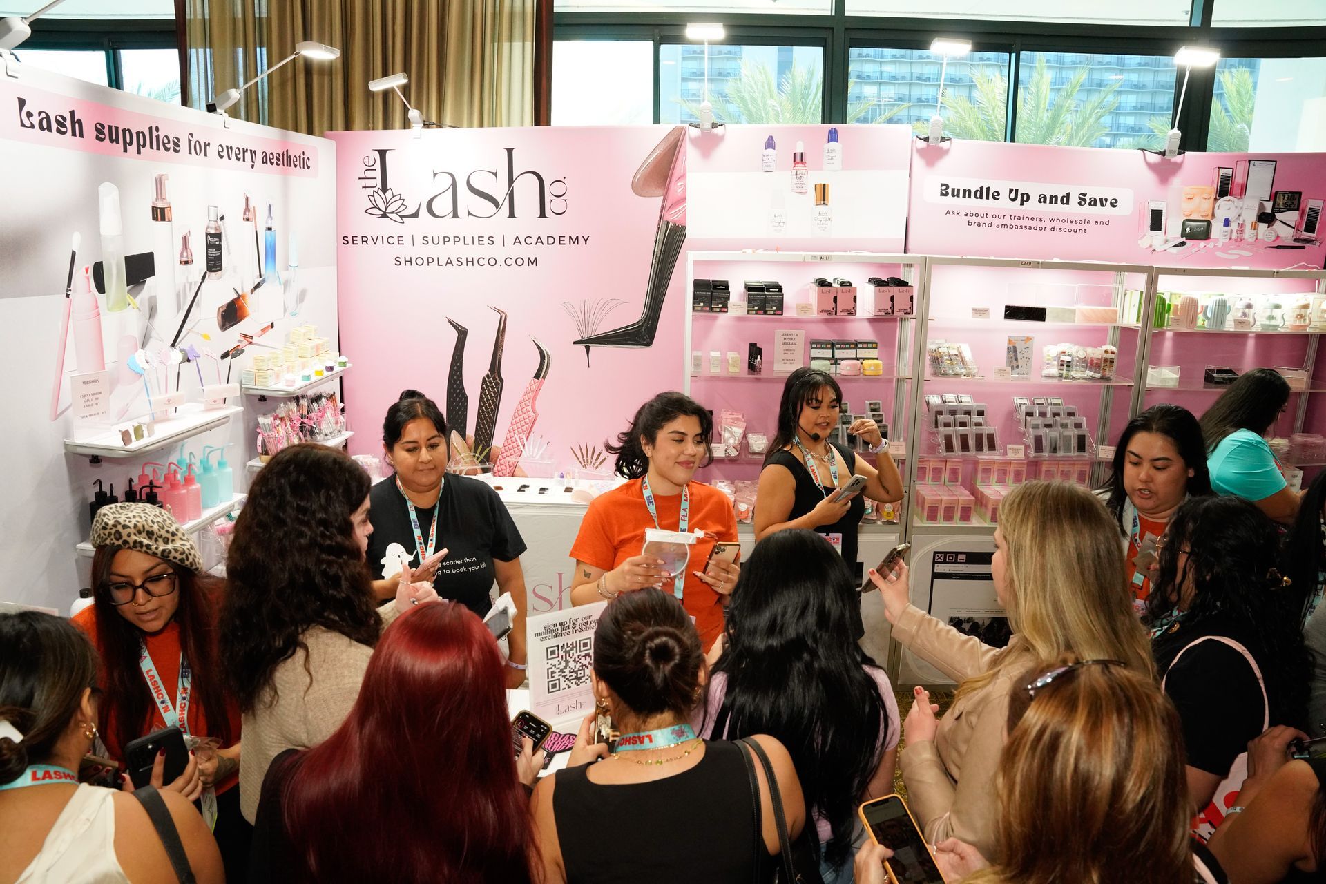 A group of women are sitting in front of a pink wall.