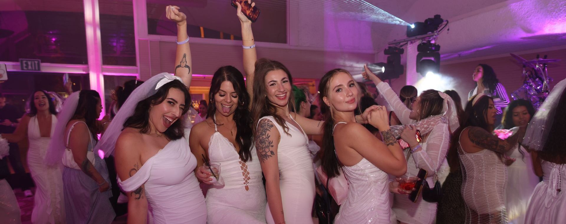 A group of women in white dresses are dancing at a party.
