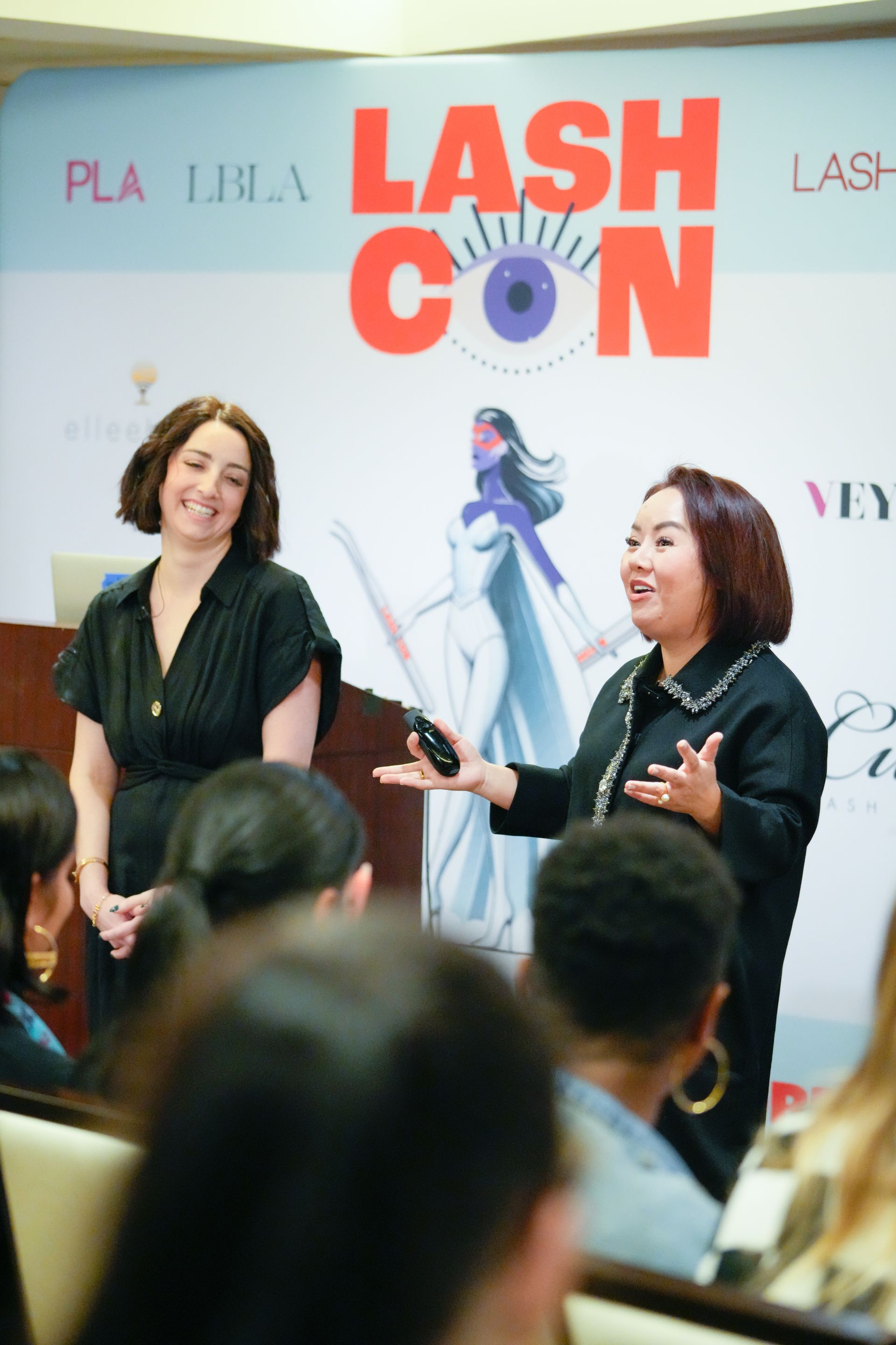 Two women are giving a presentation at a lash con