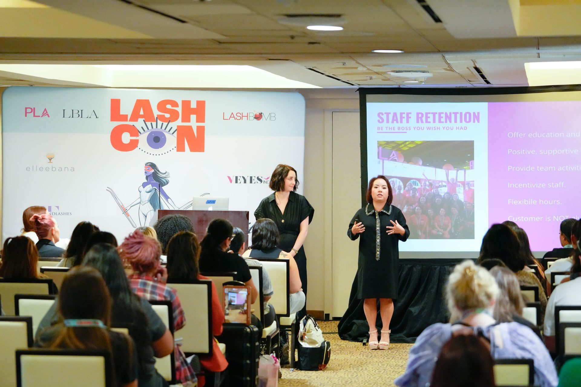 Two women are giving a presentation to a group of people at a conference.
