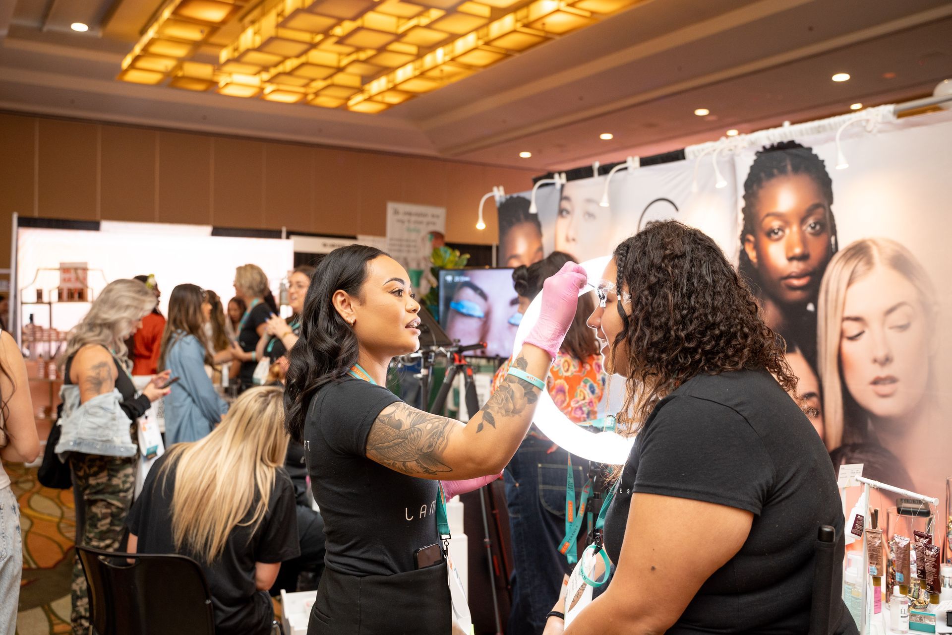 A woman is applying makeup to another woman 's face at a convention.