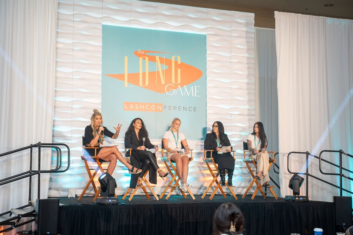 A group of women are sitting in chairs on a stage.