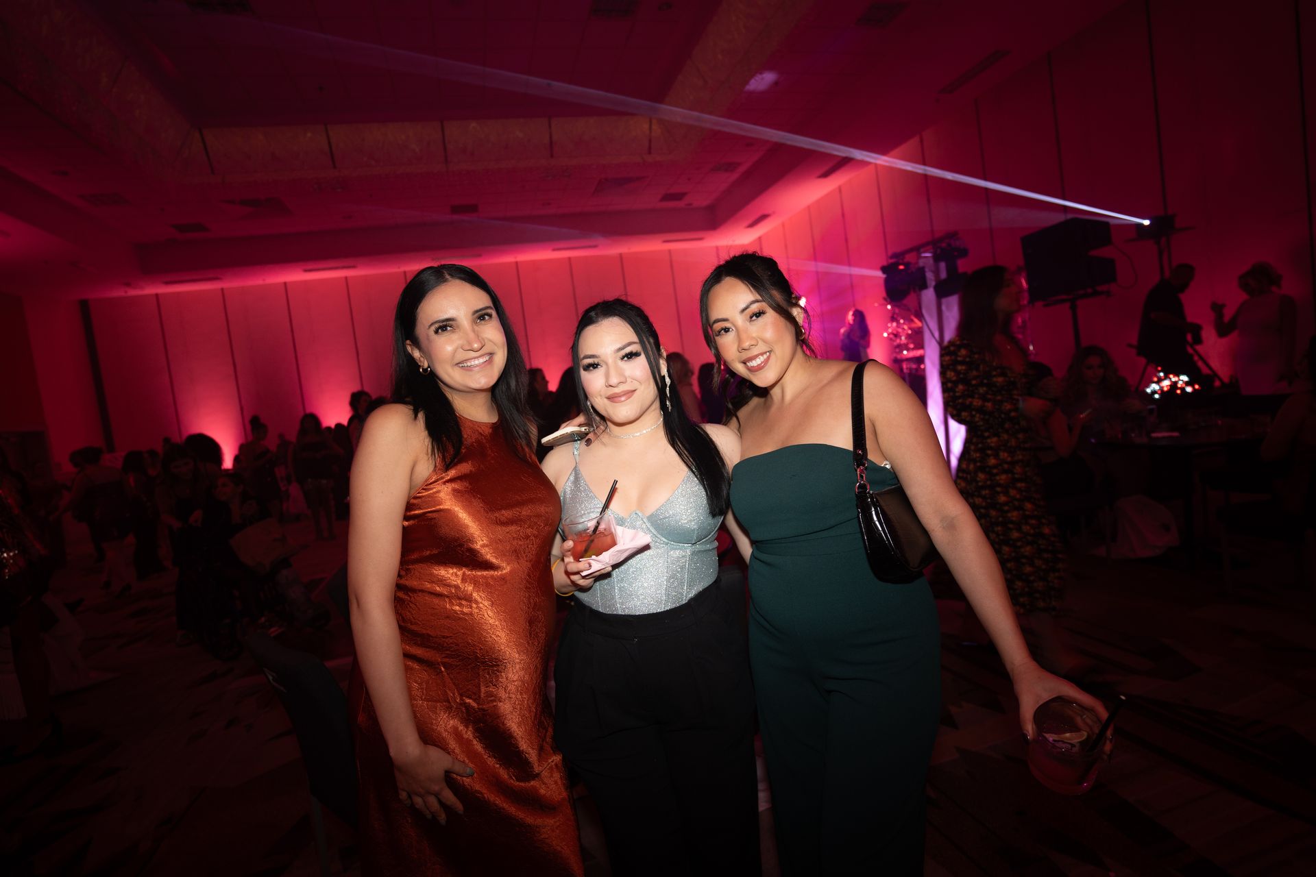 Three women are posing for a picture at a party.