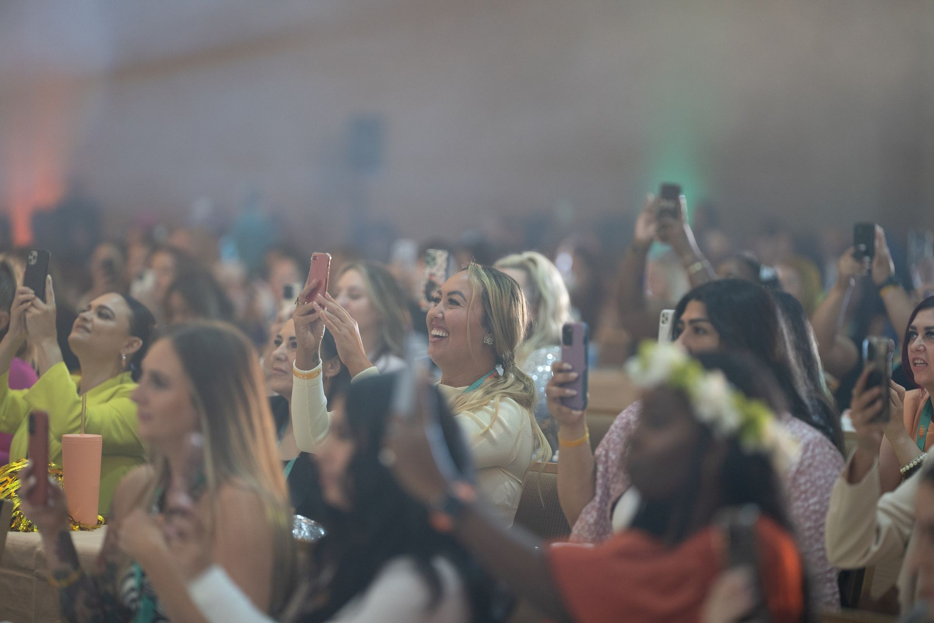A crowd of people are taking pictures with their phones at a concert.