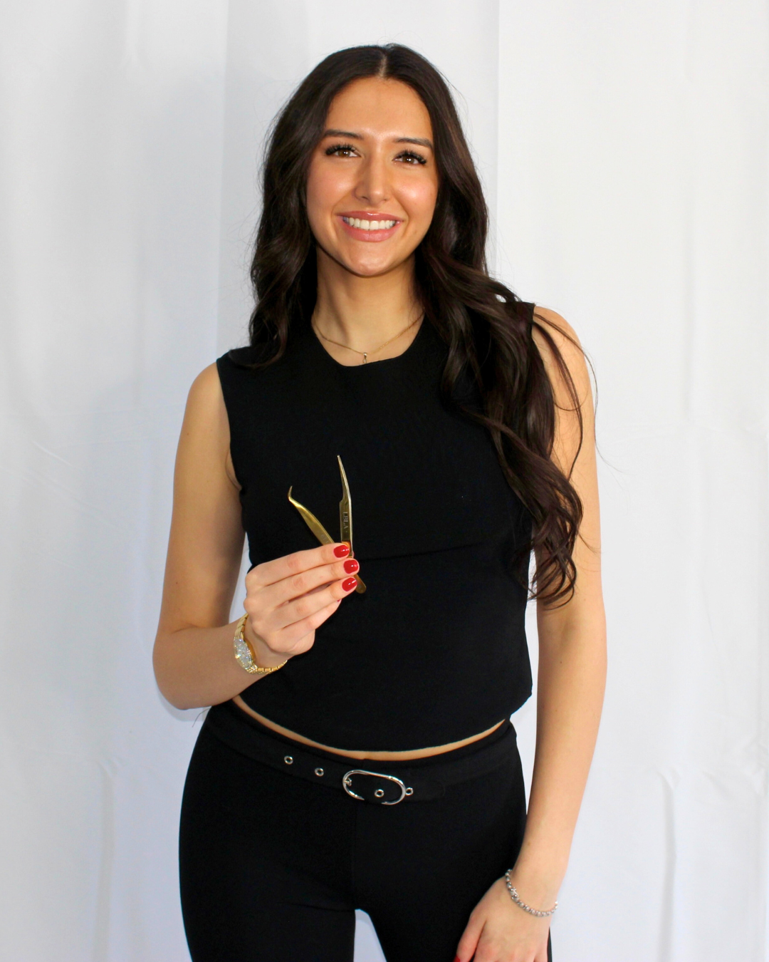 A woman in a black tank top is holding a pair of scissors