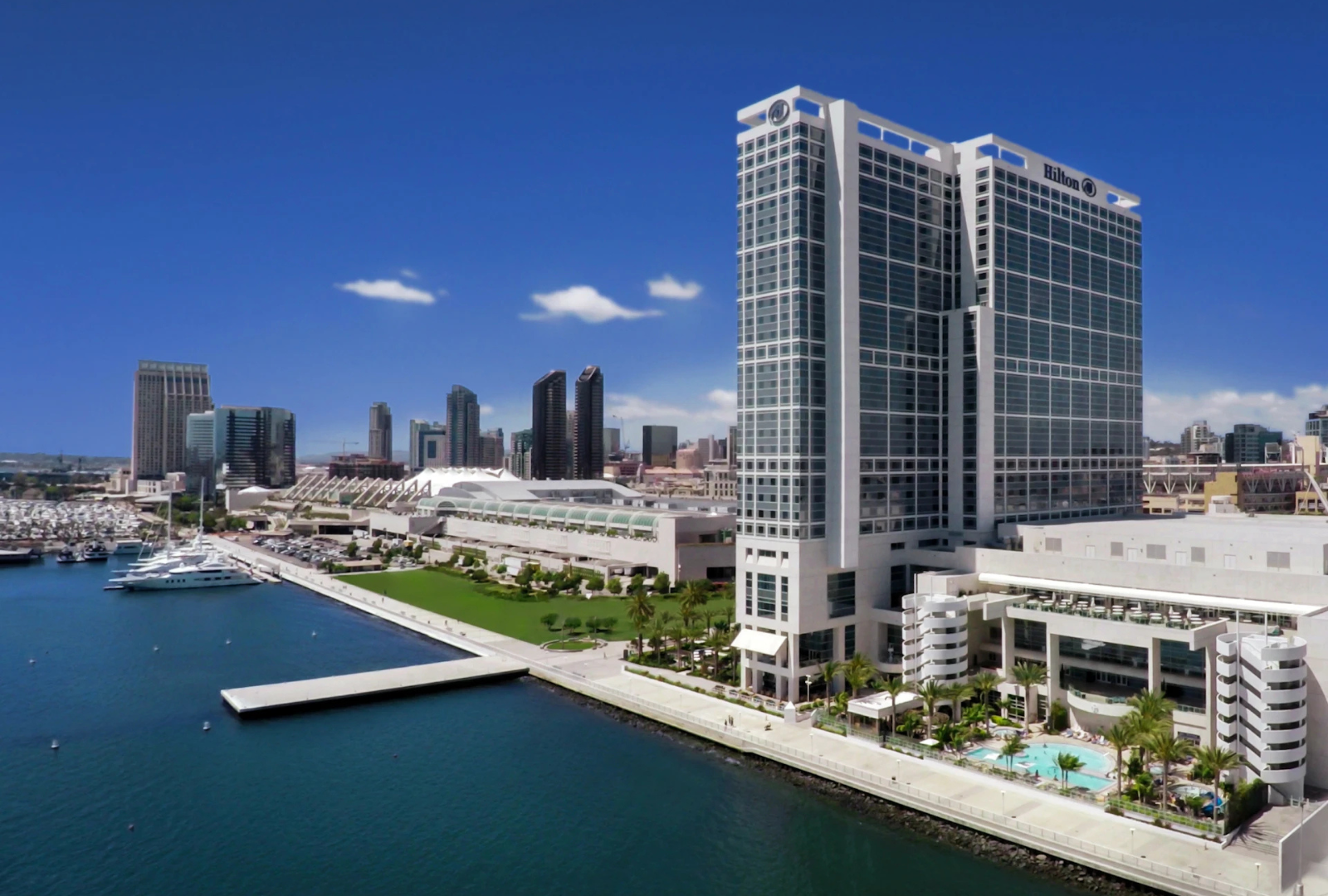 High-angle view of the Hilton San Diego Bayfront hotel along the waterfront, with the city skyline in the background.