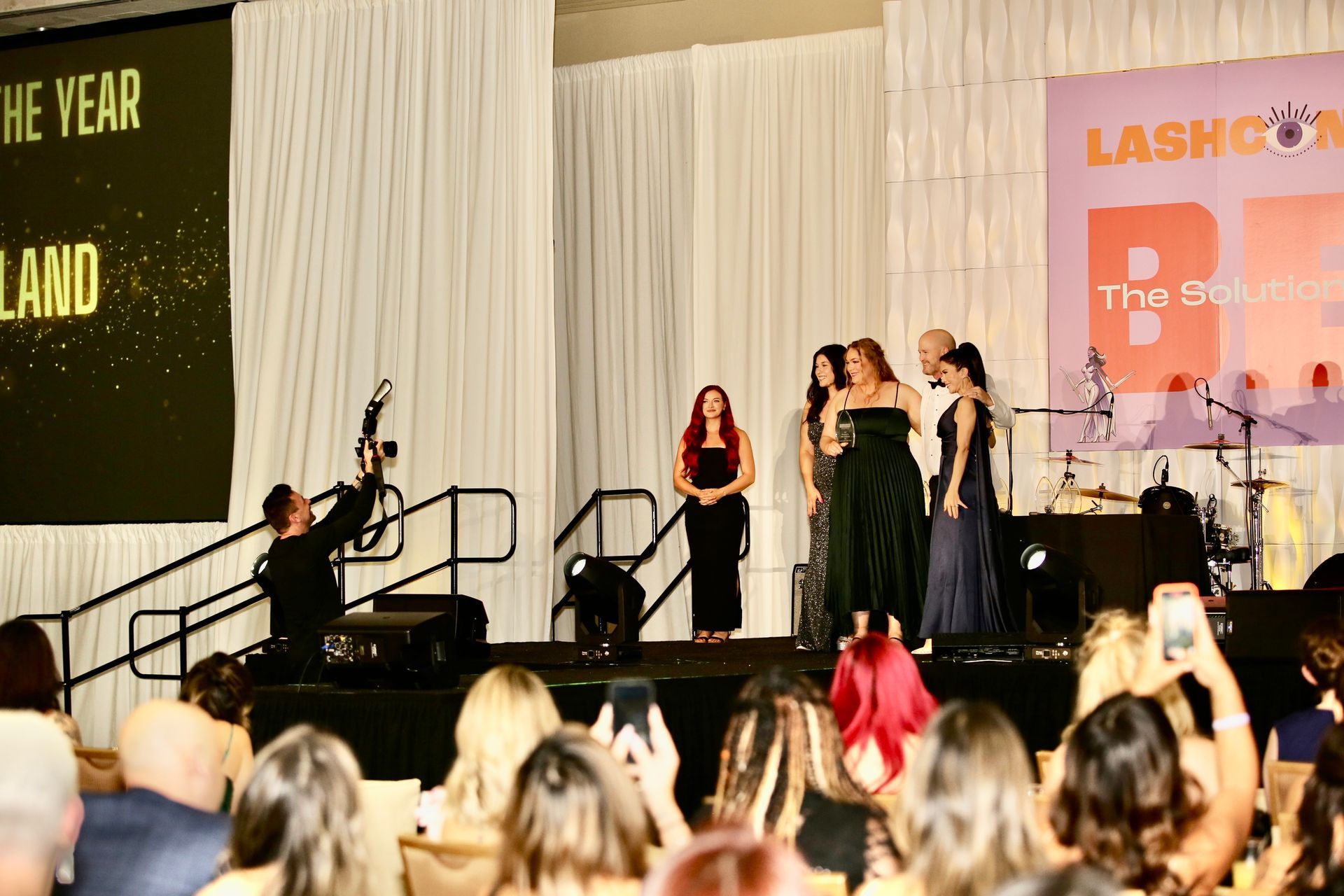 A group of women are standing on a stage in front of a crowd.