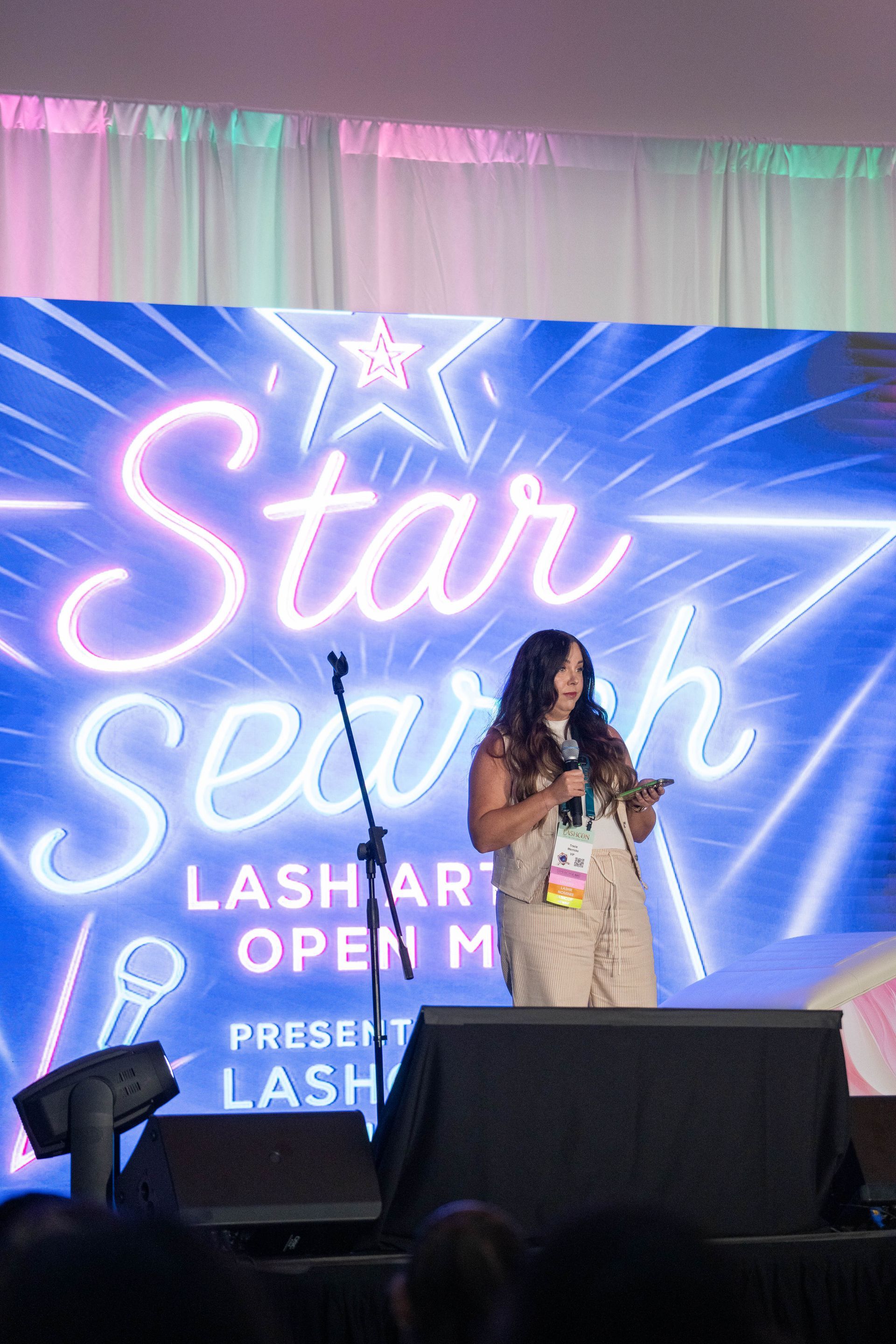 A person stands on a stage in front of a blue 
