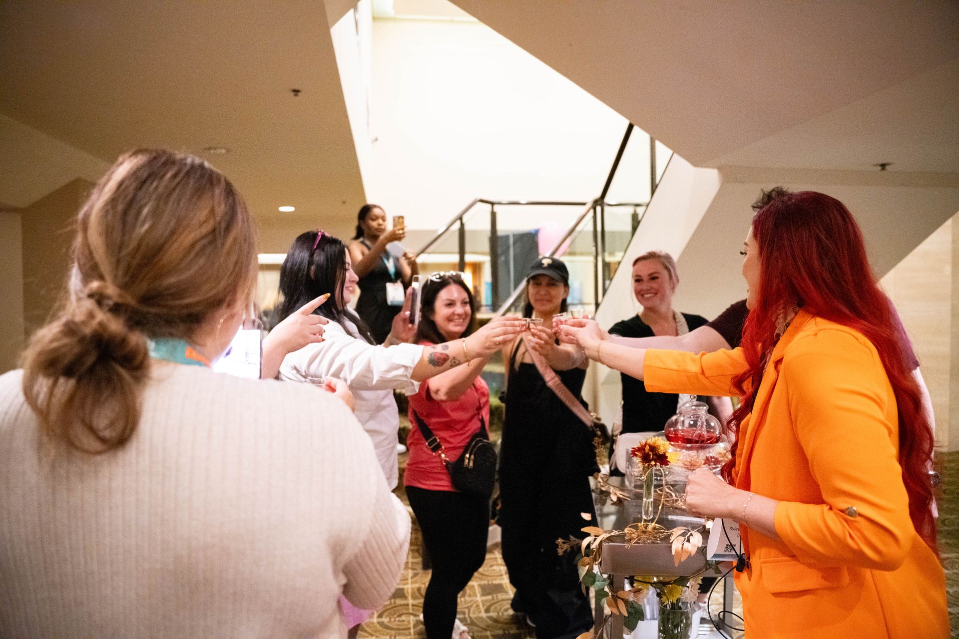 A group of women are standing around a table toasting each other.