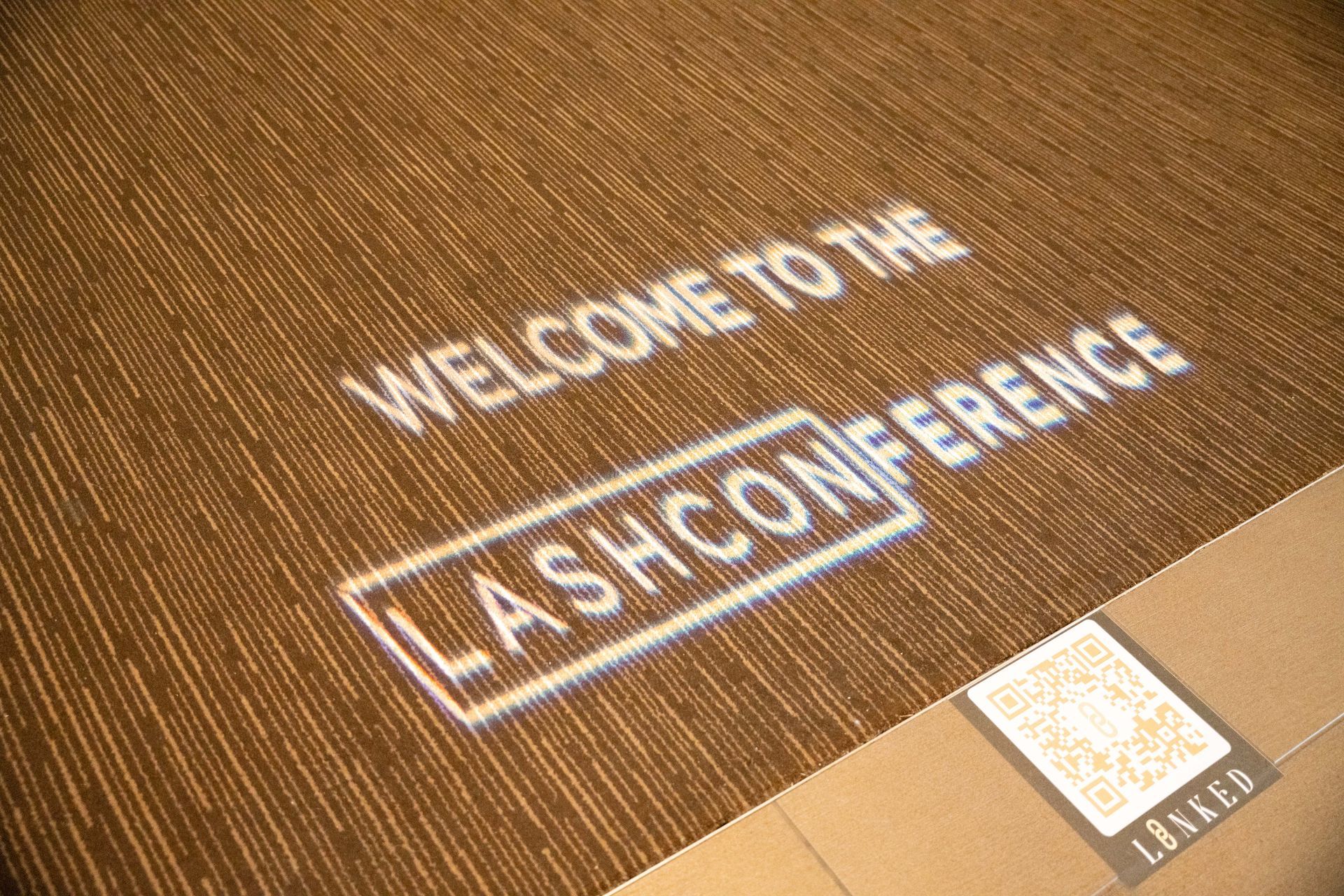 A welcome to the lash conference sign is projected on the floor.