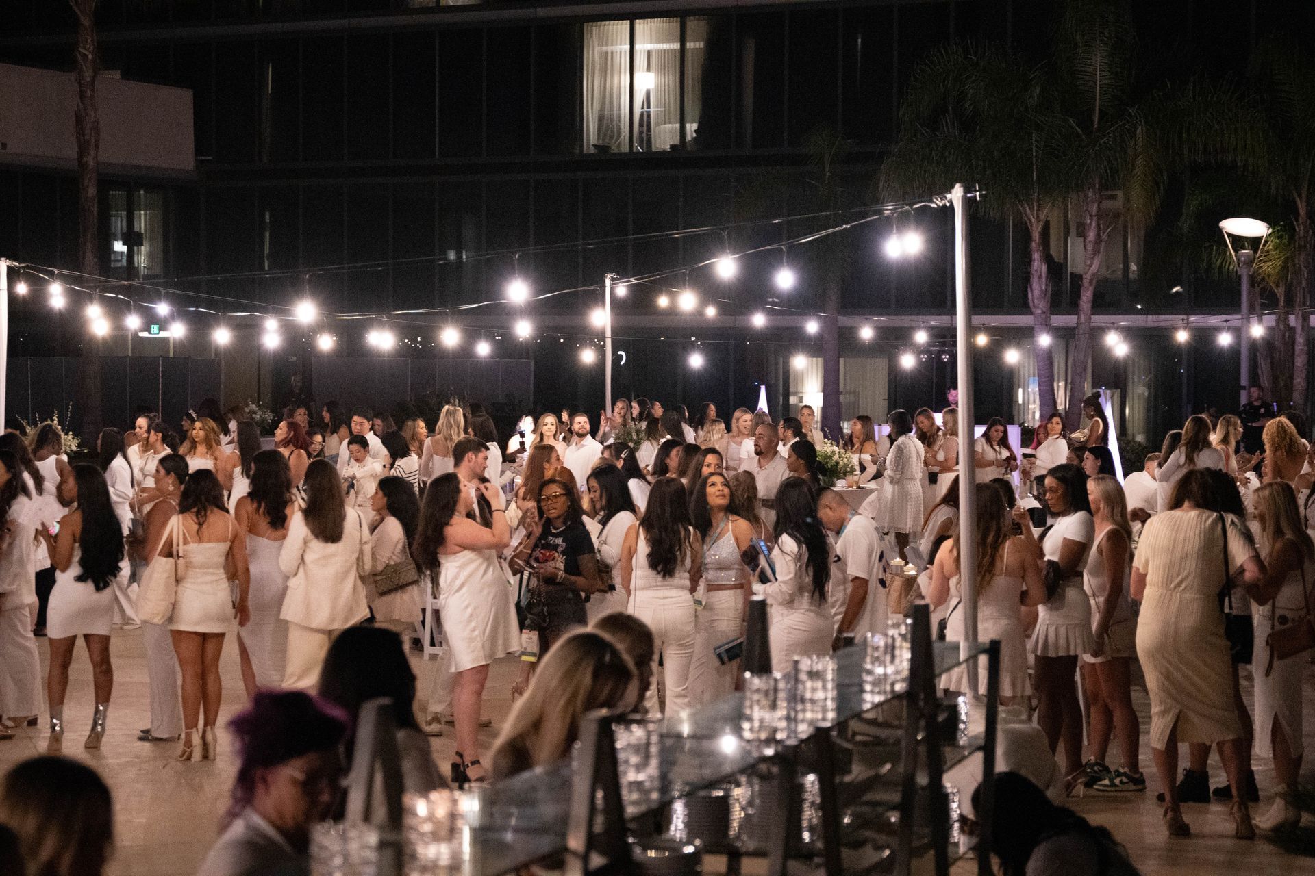 A large group of people in white dresses are dancing at a party.