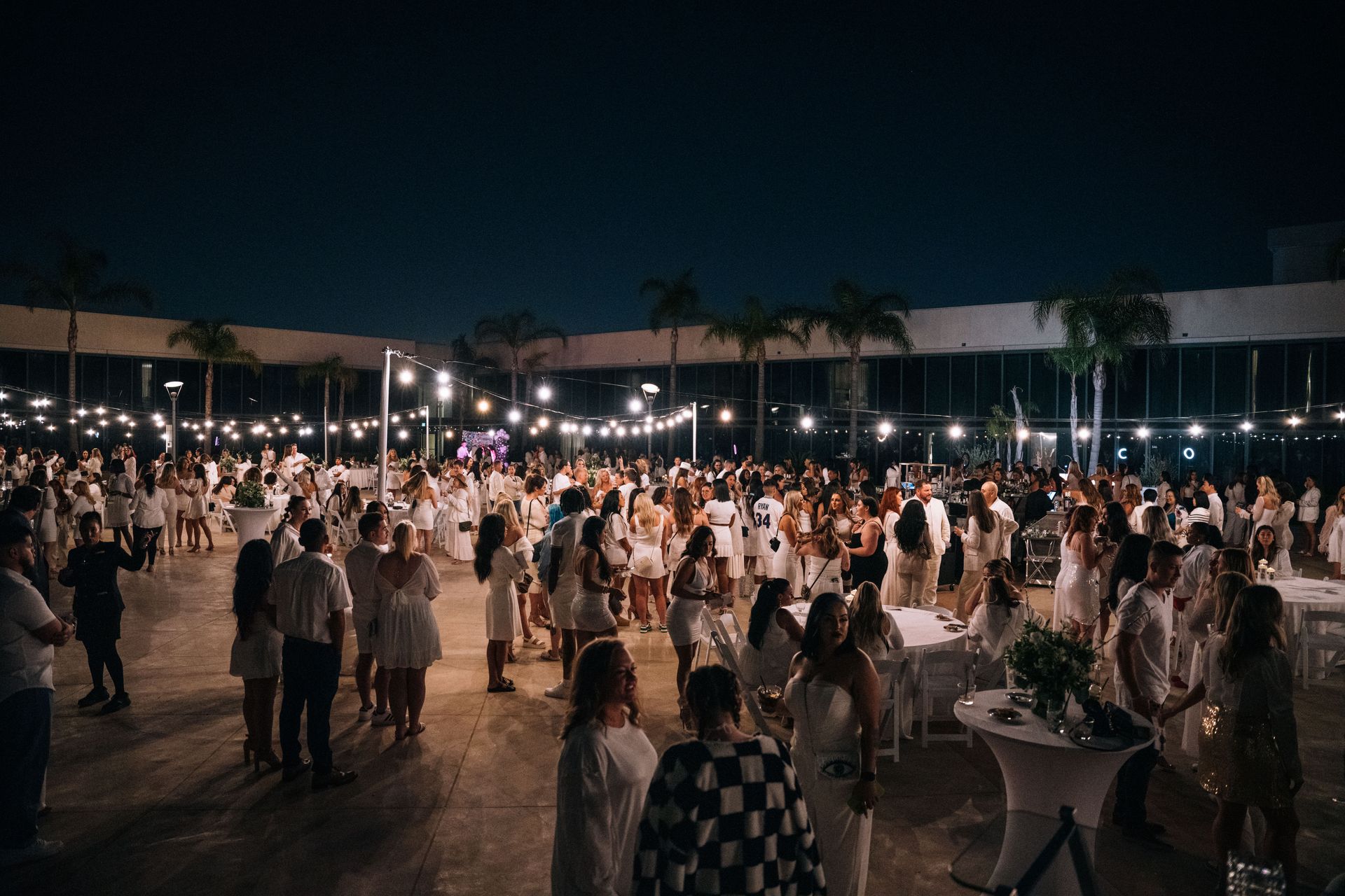 A large group of people are gathered in a large room at night.