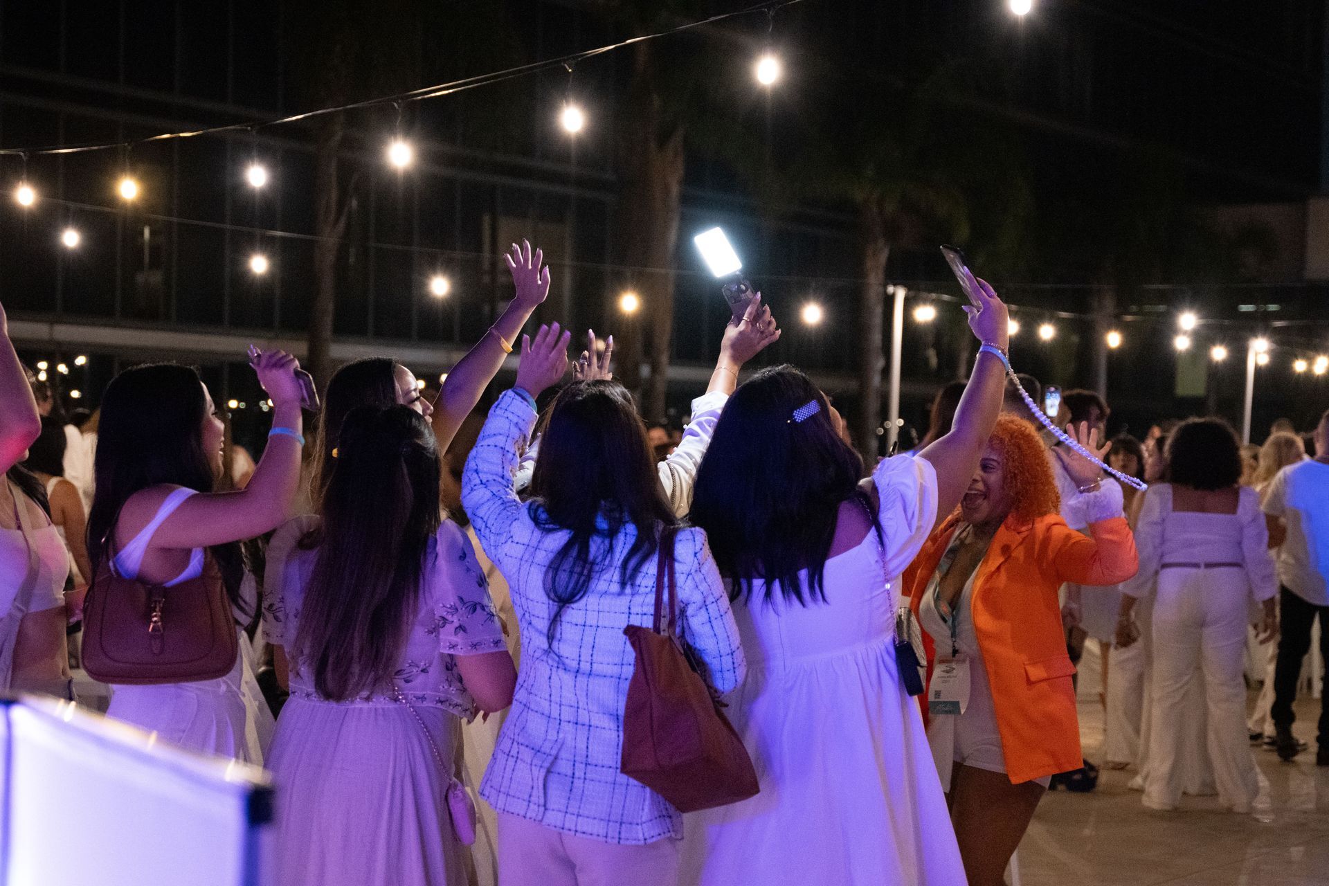 A group of women are dancing at a party with their arms in the air.