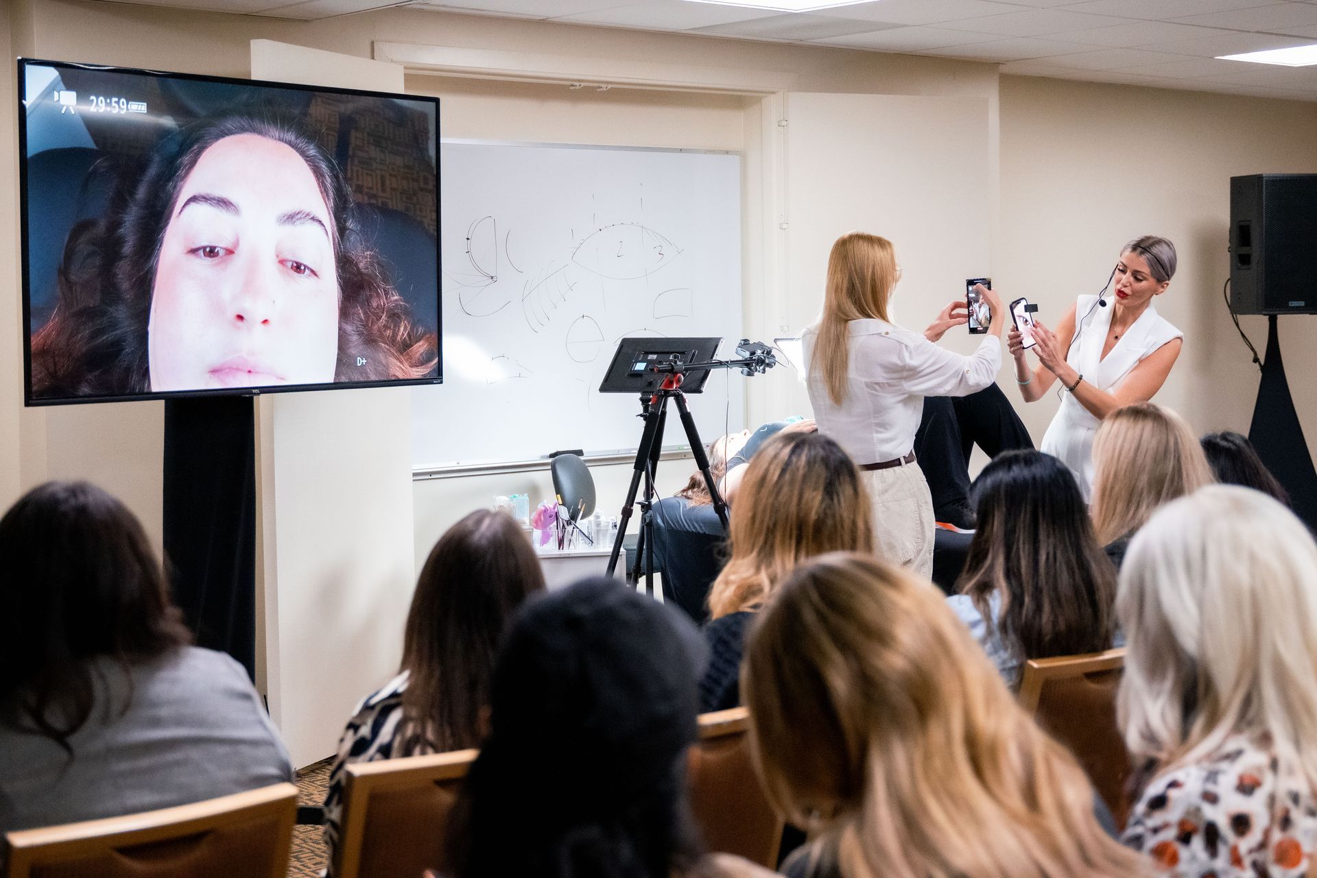 A group of women are sitting in front of a television watching a presentation.