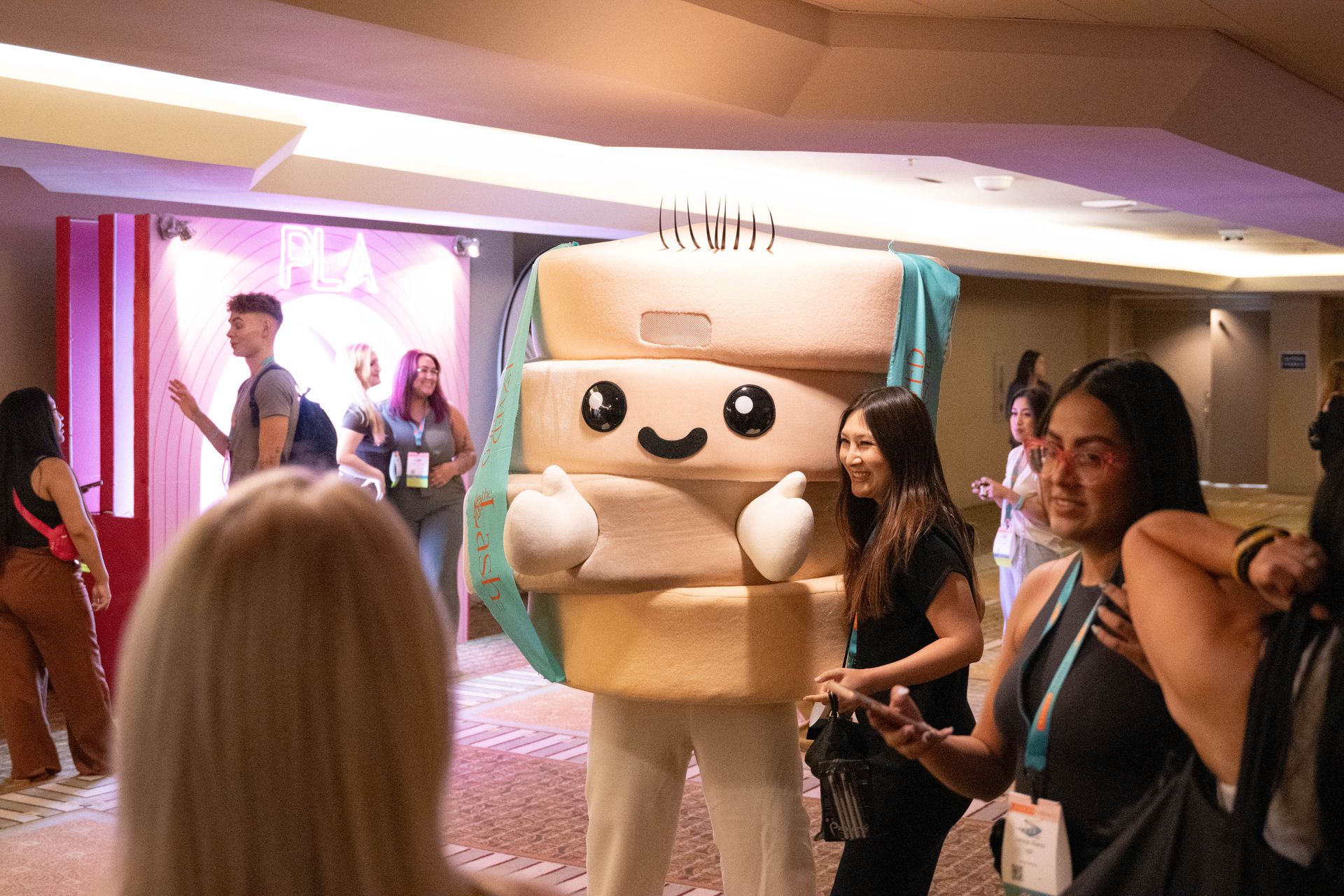A group of people are standing around a mascot in a room.