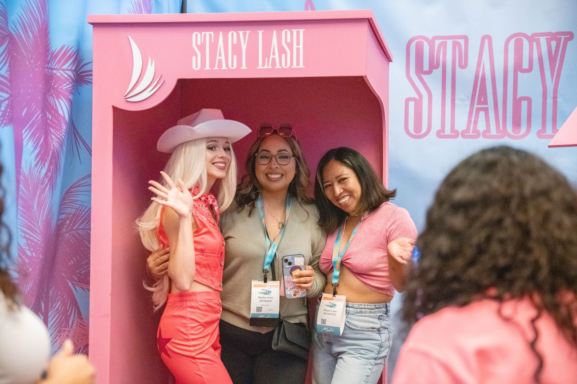 Three women are posing for a picture in a pink box.