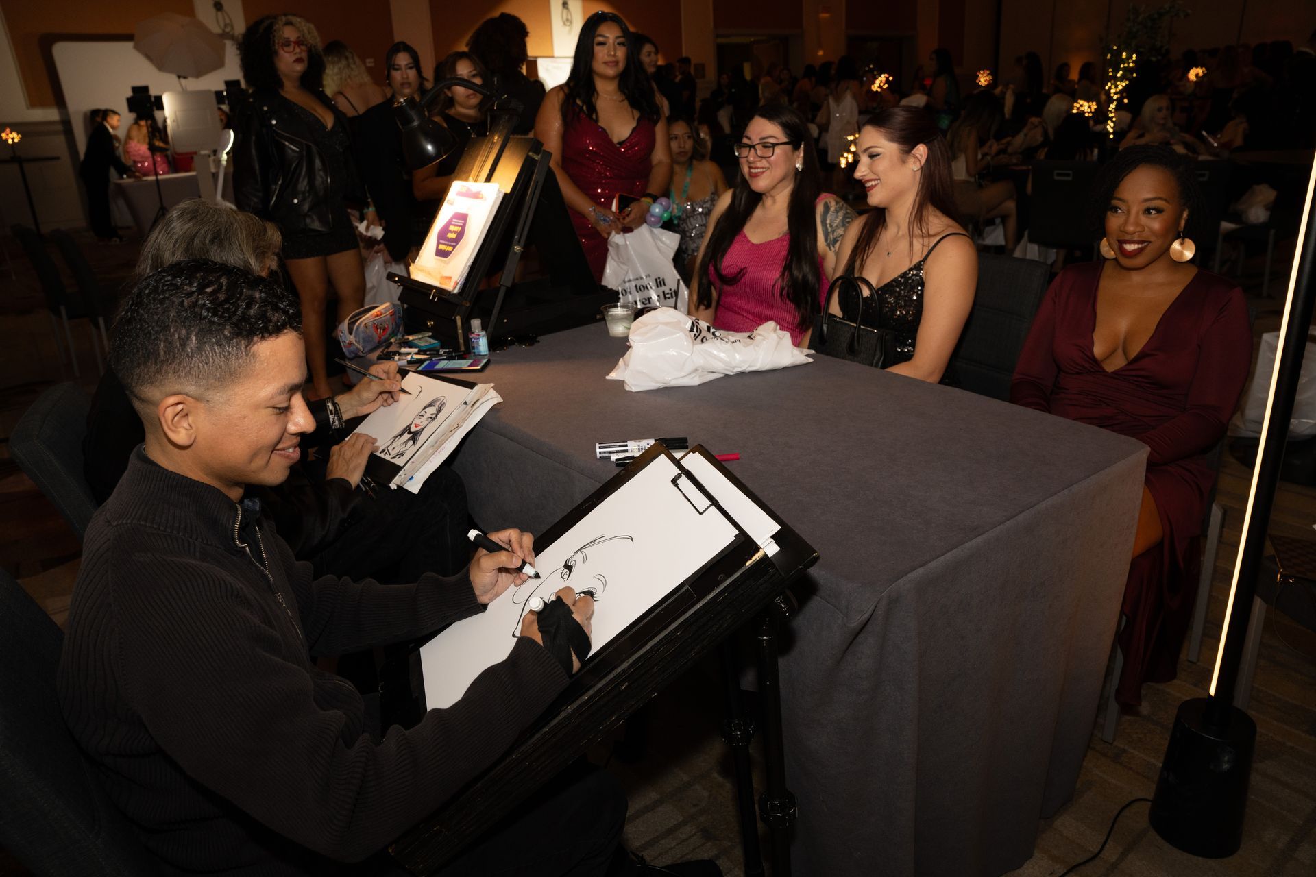 A man is sitting at a table drawing a picture of a woman.
