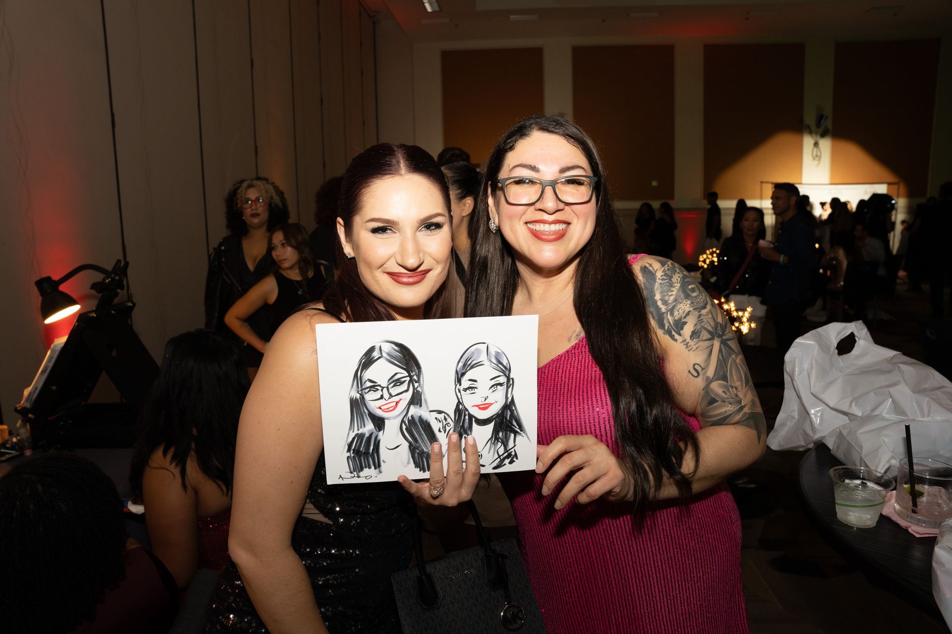 Two women are posing for a picture while holding a drawing of their faces.