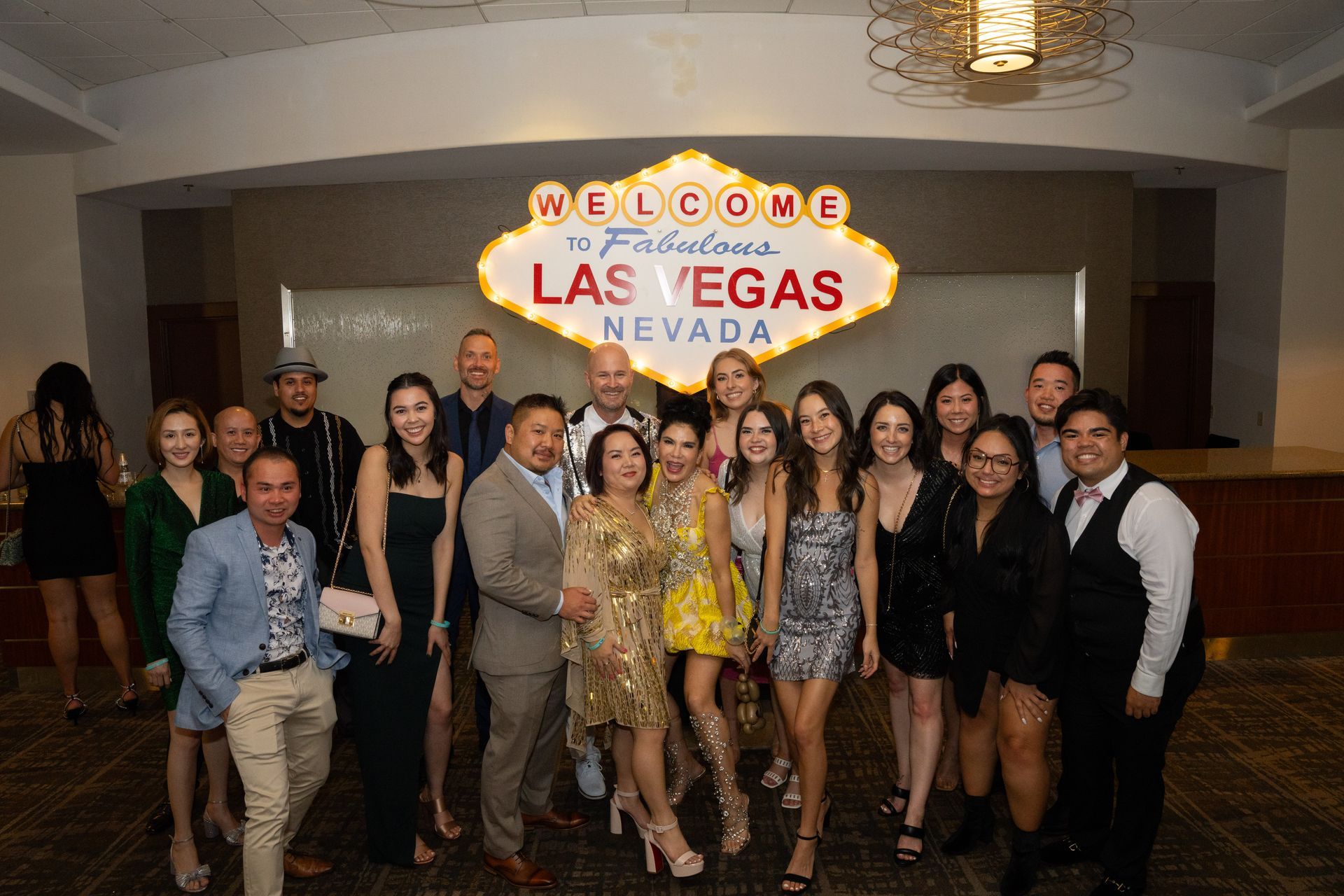 A group of people are posing for a picture in front of a las vegas sign.