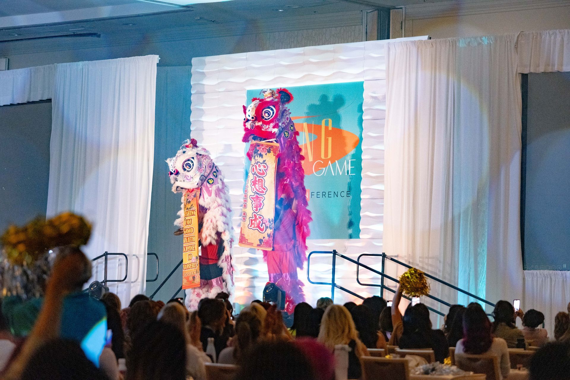 A group of people are sitting in front of a stage with a lion on it.