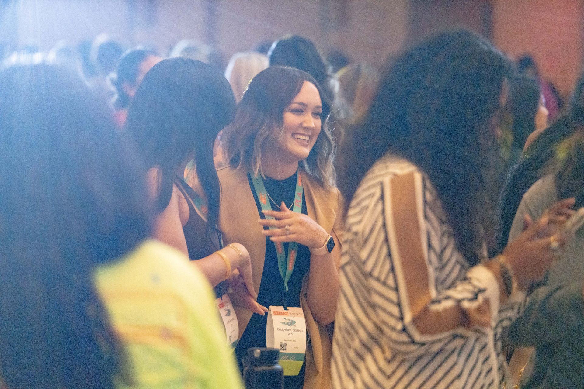 A group of women are standing in a room talking to each other.