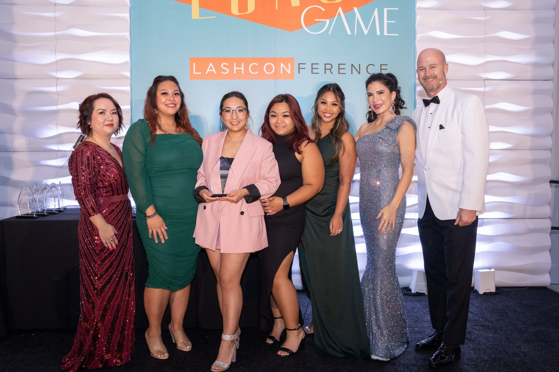 A group of women are posing for a picture at a lash conference.