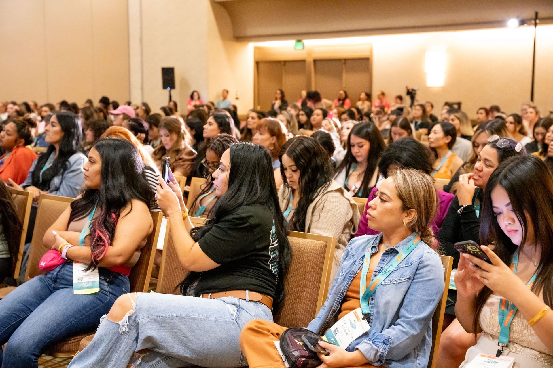 A large group of women are sitting in chairs at a conference.