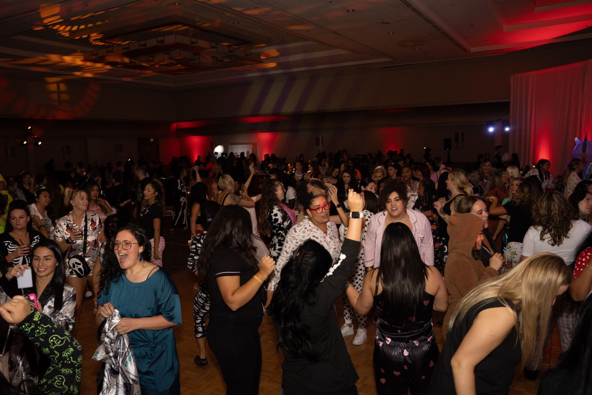 A large group of people are dancing in a large room.