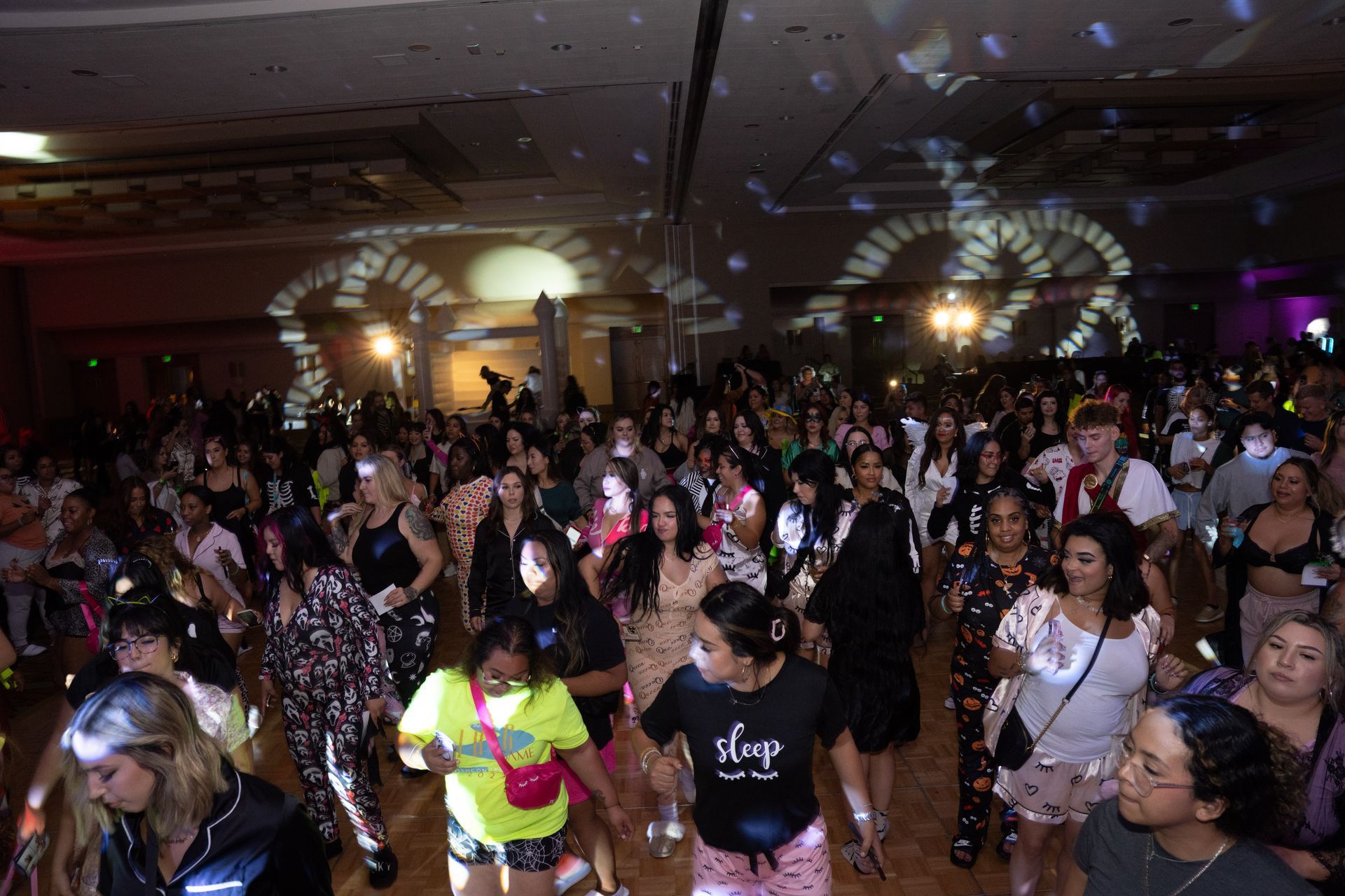 A large group of people are dancing in a large room.